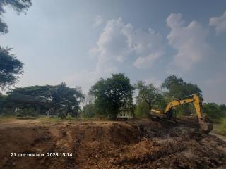 Excavator on a construction site with trees and clear sky