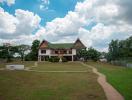 Spacious two-story house with a large front lawn and pathway under a cloudy sky