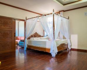 Spacious bedroom with large canopy bed and hardwood floors