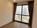 Empty bedroom with large window and city view