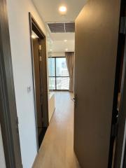 Bright corridor with wooden floor leading to a well-lit room with large windows