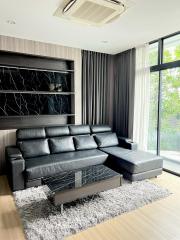 Modern living room with large black leather sectional sofa and marble coffee table