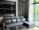 Modern living room with large black leather sectional sofa and marble coffee table