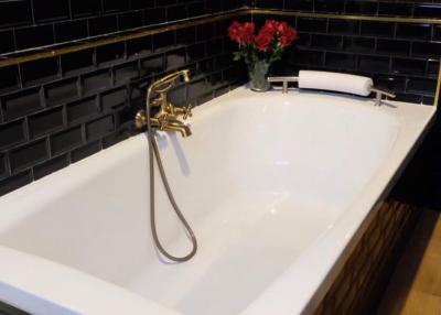 Modern bathroom with black tile walls and white bathtub