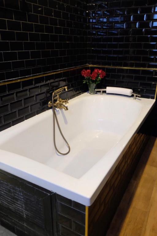 Modern bathroom with black tile walls and white bathtub