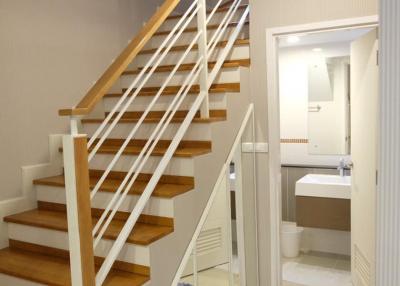 Modern staircase with wooden steps and white balustrade leading to an upper level