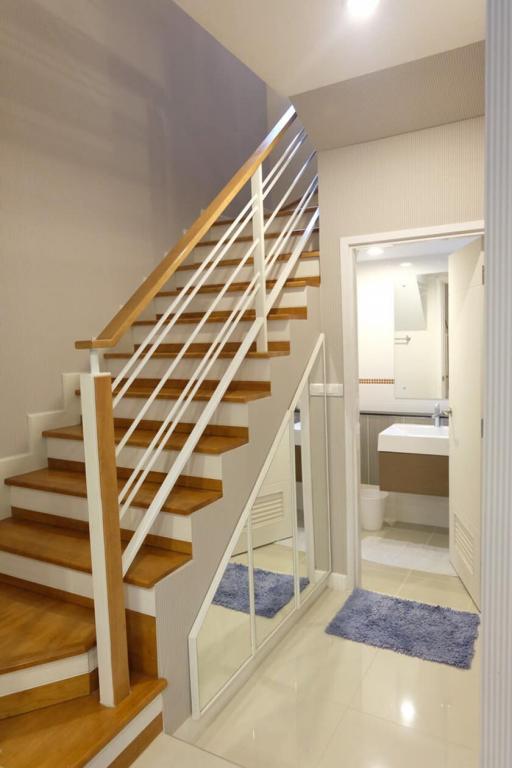 Modern staircase with wooden steps and white balustrade leading to an upper level