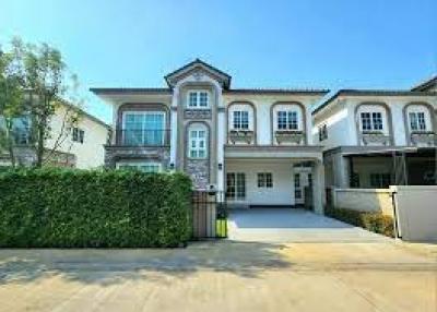 Elegant two-story house with manicured hedge and spacious driveway