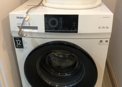 Modern white front load washing machine in a compact laundry room