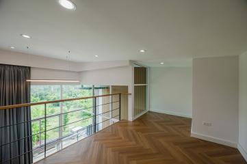 Spacious interior of a modern building with natural light, wooden flooring, and balcony access