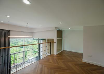 Spacious interior of a modern building with natural light, wooden flooring, and balcony access