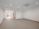 Spacious and well-lit empty living room with air conditioning and staircase