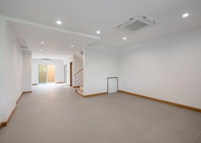 Spacious and well-lit empty living room with air conditioning and staircase