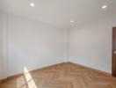 Spacious bedroom with herringbone wood flooring and natural light