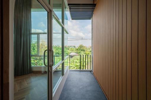 Spacious balcony with wooden paneling and a view of greenery