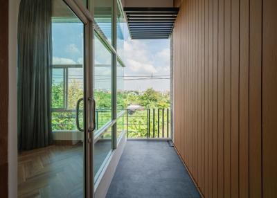 Spacious balcony with wooden paneling and a view of greenery