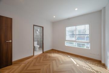 Spacious and well-lit bedroom with wooden flooring and en suite bathroom