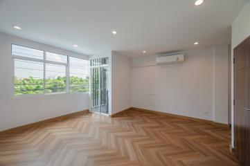 Spacious bedroom with large windows and wooden flooring