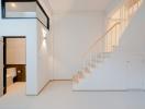 Modern interior with white walls featuring a staircase and a glimpse into the bathroom