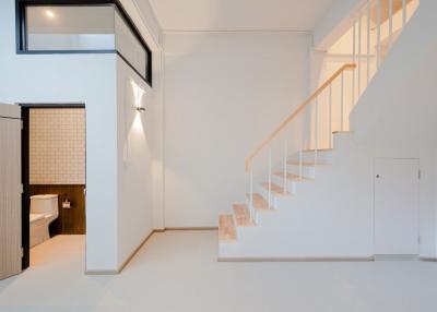Modern interior with white walls featuring a staircase and a glimpse into the bathroom