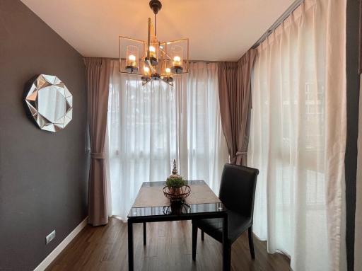 Modern dining room with elegant chandelier and large window with flowing curtains