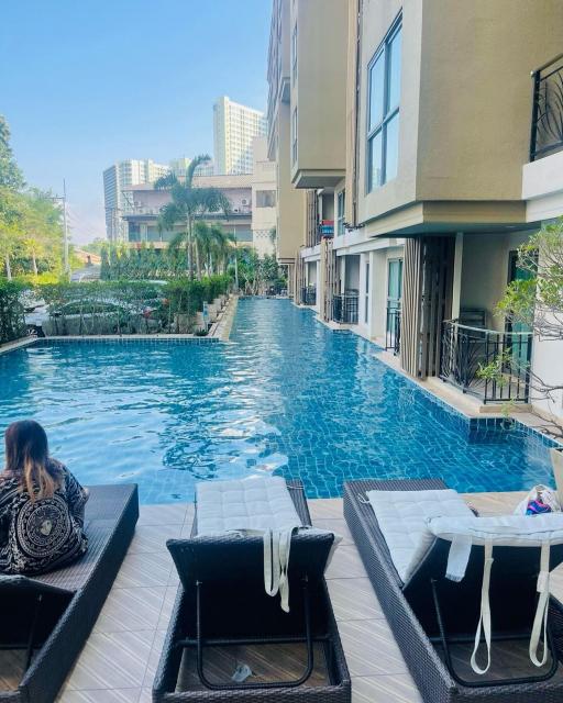 Luxurious pool area with sun loungers and modern apartment buildings in the background