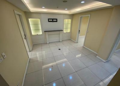 Spacious, well-lit empty room with tiled flooring and recessed lighting
