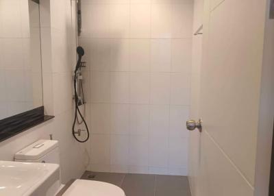 Modern white tiled bathroom with shower and toilet