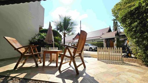 Patio area with wooden chairs and umbrella in a sunny day