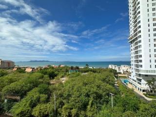 Scenic view from a high-rise apartment overlooking a coastal area with greenery and buildings