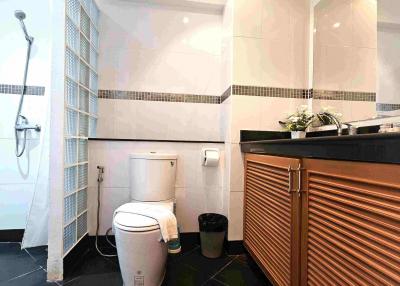 Modern bathroom with white and beige tiles, shower, and wooden vanity