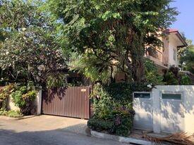 Exterior view of a residential house with a gate and lush greenery