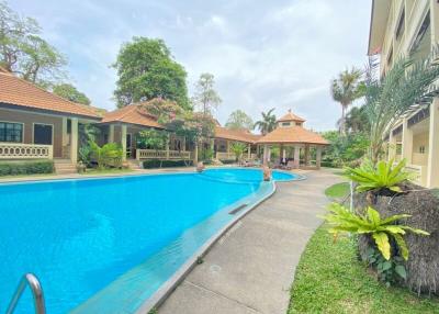 Spacious outdoor pool area with lush greenery and adjacent residential building