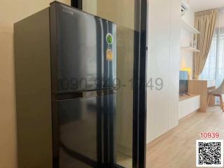 Modern apartment interior view showing a kitchen with a stainless steel refrigerator and a glimpse of the living area