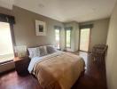 Spacious bedroom with large bed, hardwood floors and ample natural light