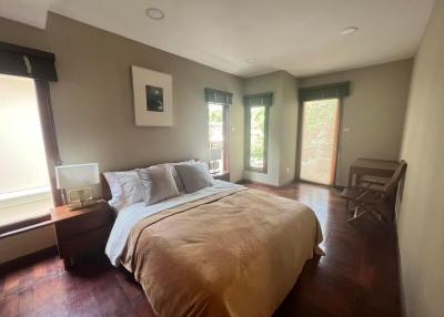 Spacious bedroom with large bed, hardwood floors and ample natural light