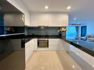 Modern kitchen with black countertops and stainless steel appliances leading to an open living area