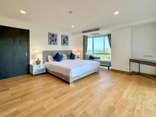 Spacious bedroom with ocean view, natural light, and hardwood flooring