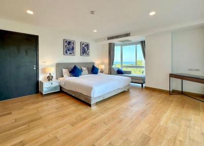 Spacious bedroom with ocean view, natural light, and hardwood flooring