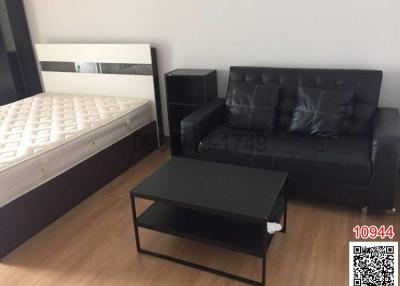 Compact bedroom with a double bed, a black sofa, and a coffee table