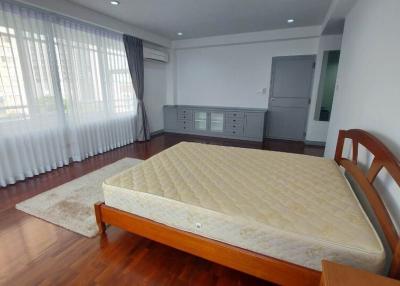 Spacious bedroom with large bed, hardwood floors, and ample natural light