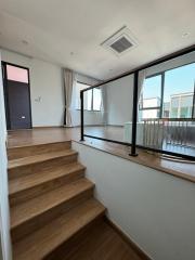 Modern staircase with wooden steps leading to a loft space with balcony doors and ample natural light