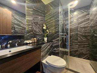 Modern bathroom with dark marble walls and glass shower cabin