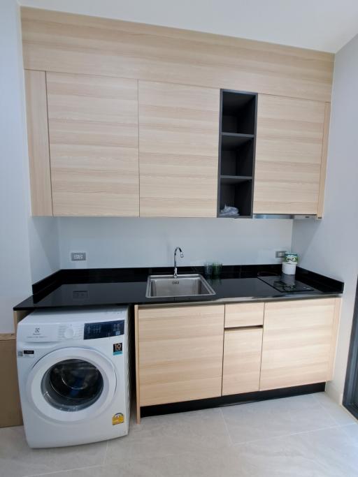 Modern compact kitchen with light wood cabinetry and built-in appliances