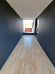 narrow residential hallway with wooden flooring leading to a door