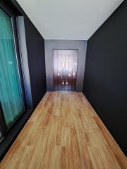 Narrow corridor with wooden flooring leading to a modern door