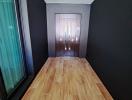 Narrow corridor with wooden flooring leading to a modern door