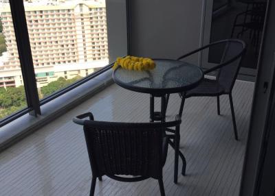 Modern balcony with glass table and chairs overlooking a cityscape