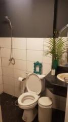 Modern bathroom with white and black tiles featuring toilet, sink, and shower