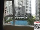 View from the window of a high-rise apartment showing a swimming pool and other buildings